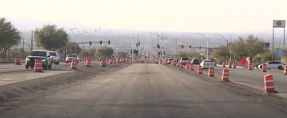 Barrels channeling traffic through the Boulder Highway corridor with exposed soil on both sides