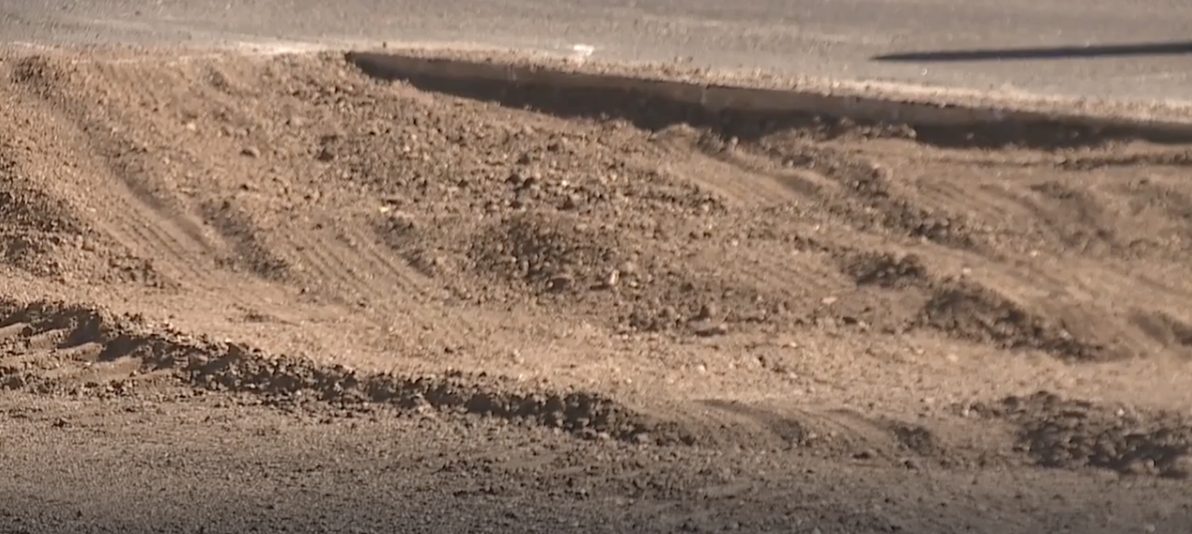 Close-up of loose disturbed soil churned by equipment tire tracks next to the travel lanes